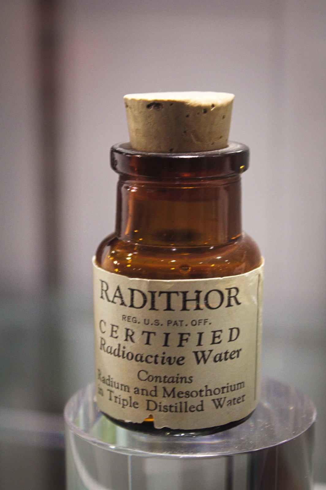 Small glass bottle with a paper label reading Radithor, Certified Radioactive Water.