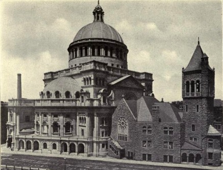 Black-and-white period photograph of a large domed church building (the Mother Church Extension) beside an older stone church tower, seen from a street corner.