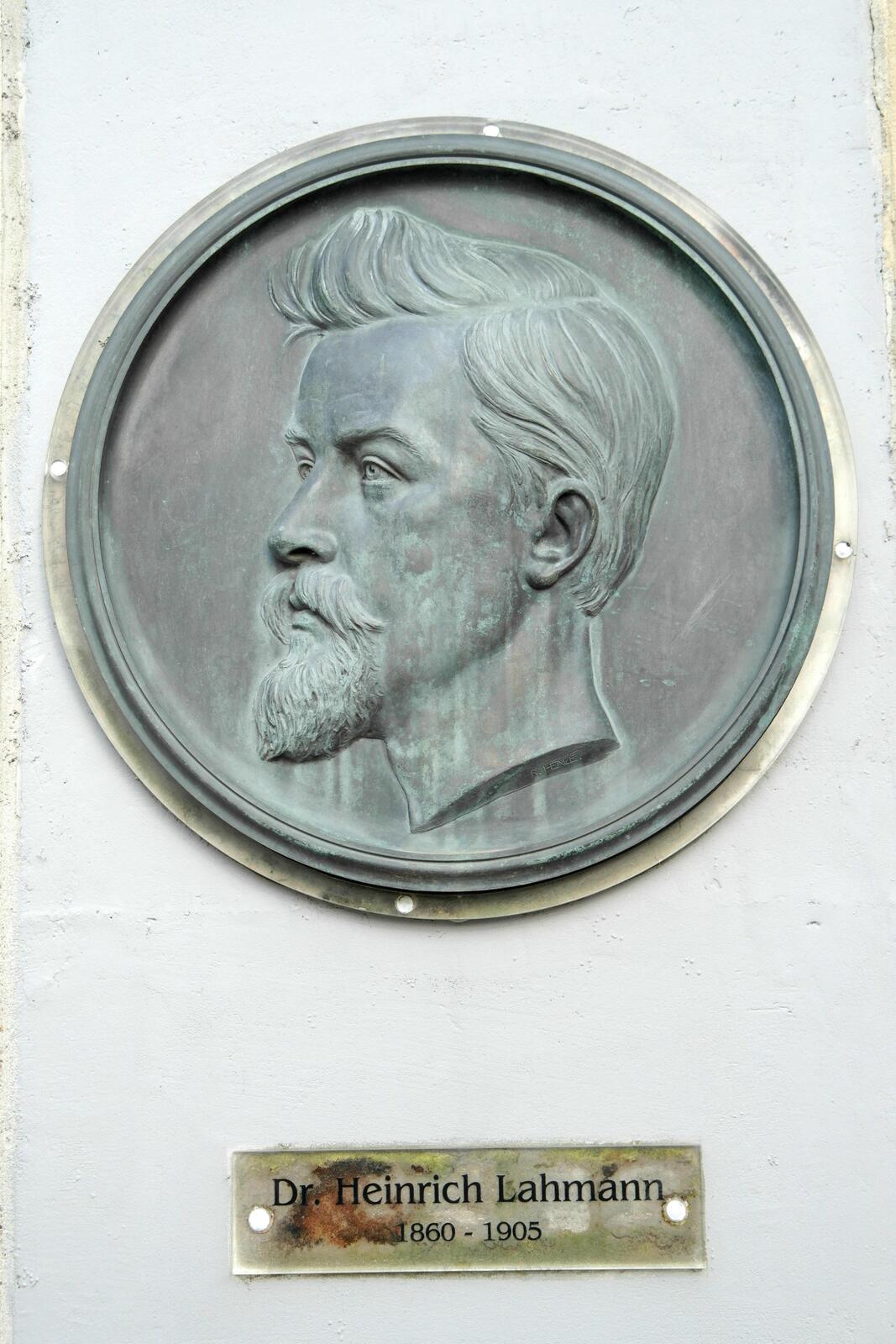 A circular bronze relief medallion showing the profile bust of a bearded man, mounted on a plastered wall above a plaque reading 'Dr. Heinrich Lahmann 1860 - 1905.'