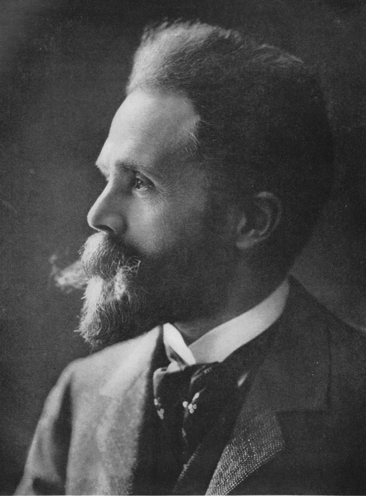 Black-and-white studio profile portrait of an elderly bearded man wearing a wing collar, bow tie, and a jacket with a fur or wool collar.
