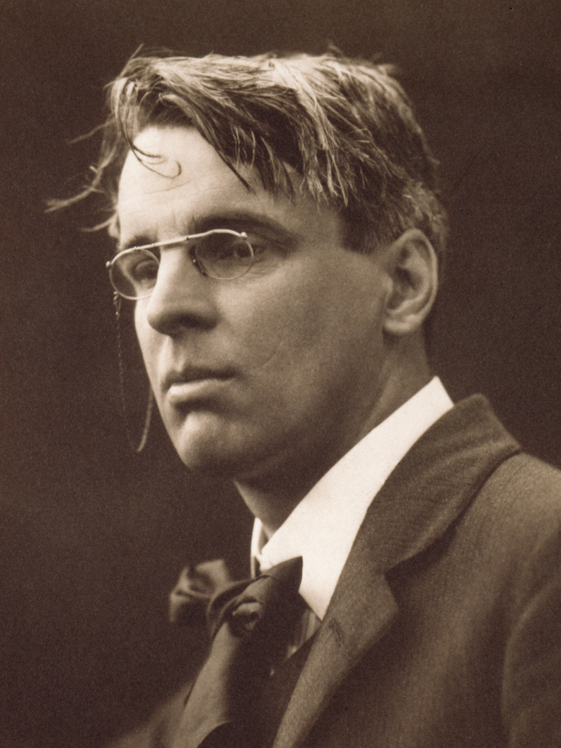 Sepia-toned portrait photograph of W. B. Yeats, a man in his mid-forties wearing a dark jacket and tie.